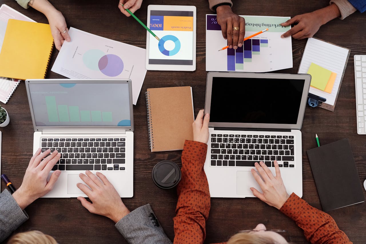 Overhead view of a team discussing digital marketing strategies with laptops and charts.